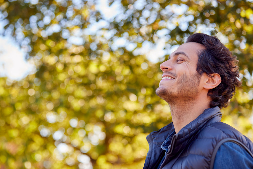 Man smiling with relief outside after addiction therapy session.